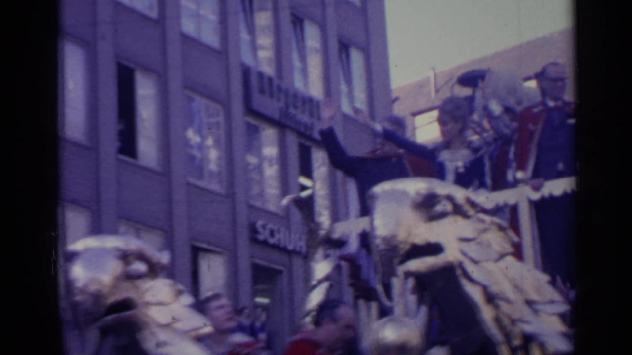 Close street-level view of a parade float with waving figures and eagle sculpture.