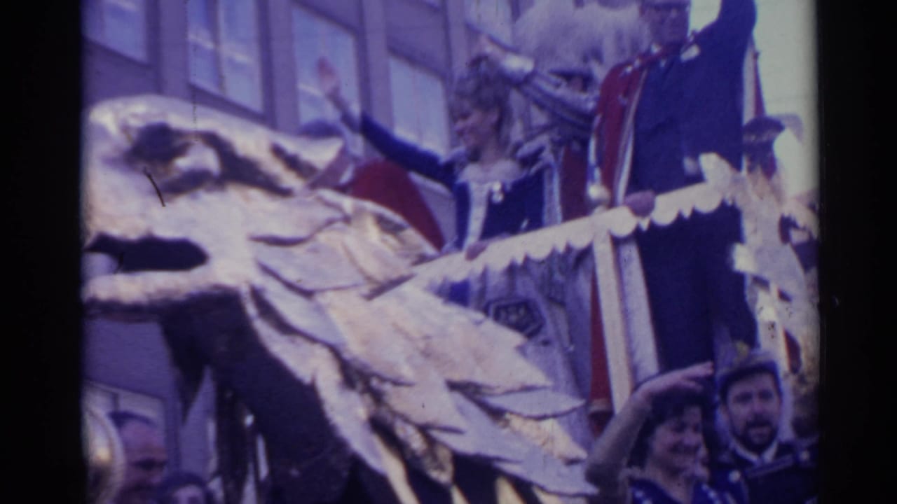 Decorated parade float with a large gold eagle head and people waving behind it.