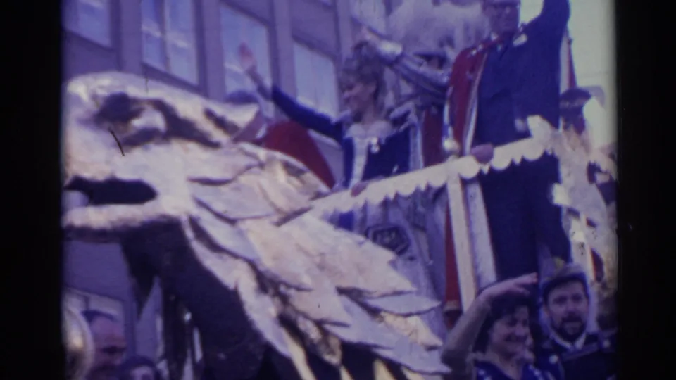1961 Spain home-movie frame showing a gold eagle-headed parade float with costumed adults waving from behind the railing.