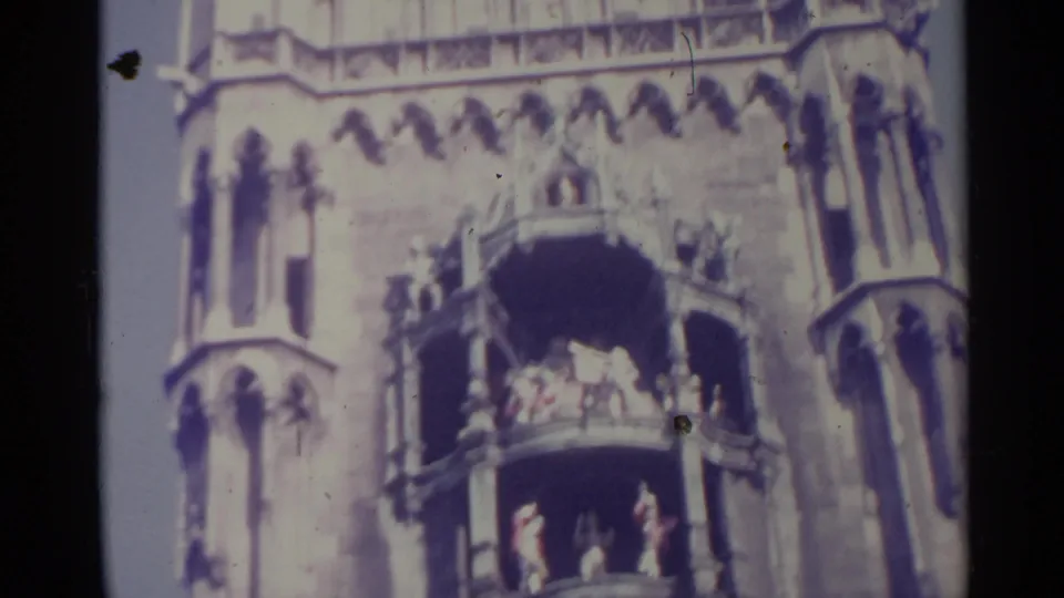1961 Spain 8mm frame of a Gothic-style facade, with distant people gathered on two balcony levels.