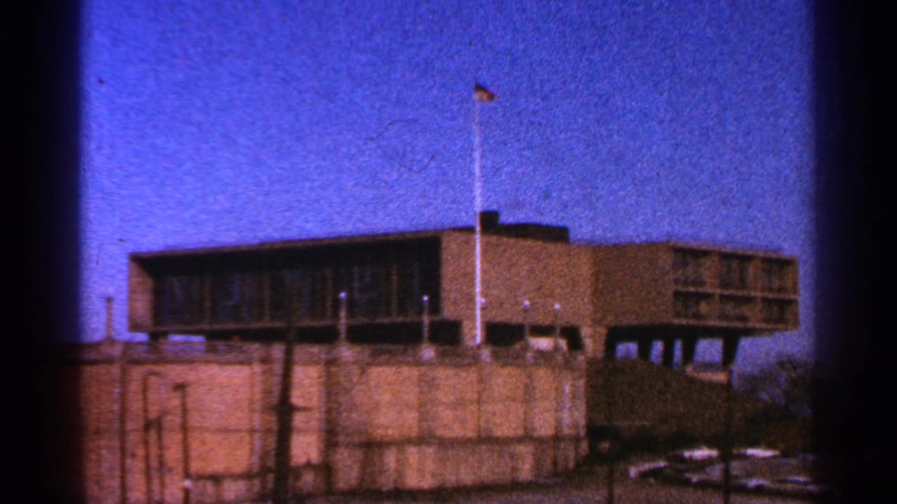 Brown modernist building with an American flag on a tall pole under a blue sky.