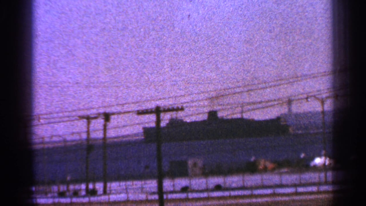 1964 Milwaukee port view with a large ship on the water, utility poles, wires, and a dark window-frame edge in the foreground.