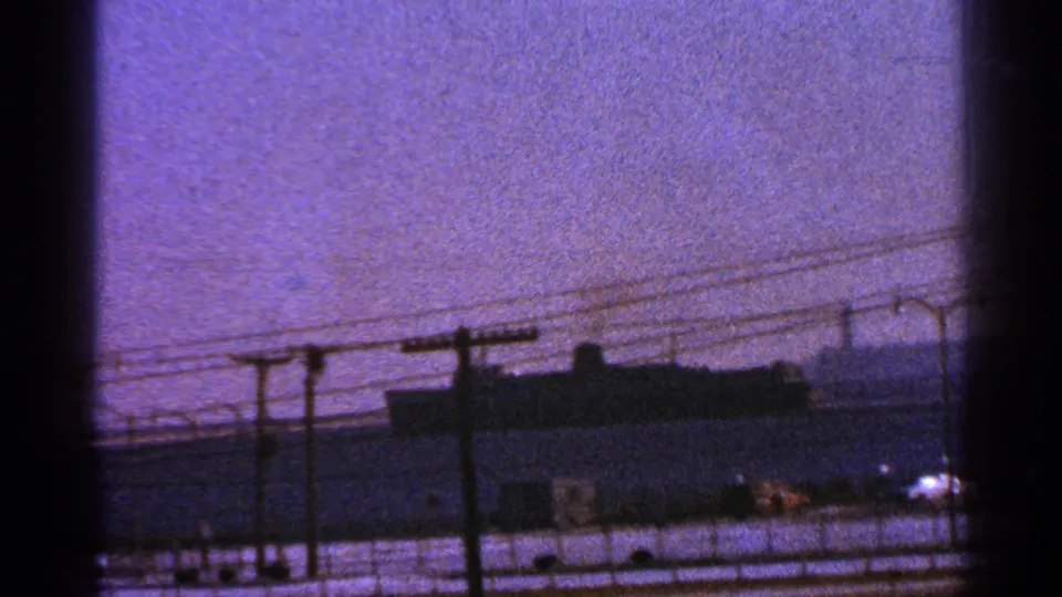 A large vessel near the Milwaukee waterfront appears behind utility poles and wires, framed by dark edges of the filmed viewpoint.