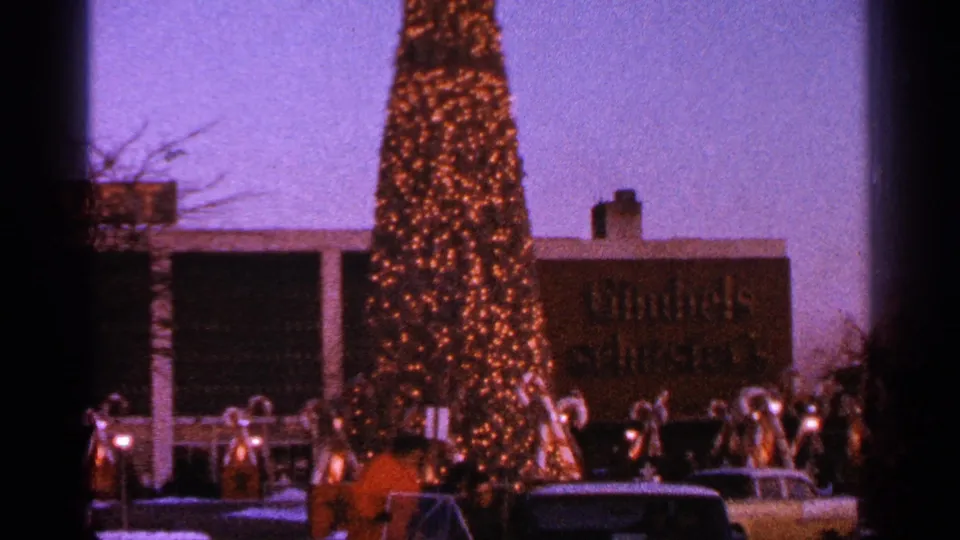 1964 Milwaukee frame showing illuminated holiday figures and a star below a tall Christmas tree outside the Gimbels storefront.