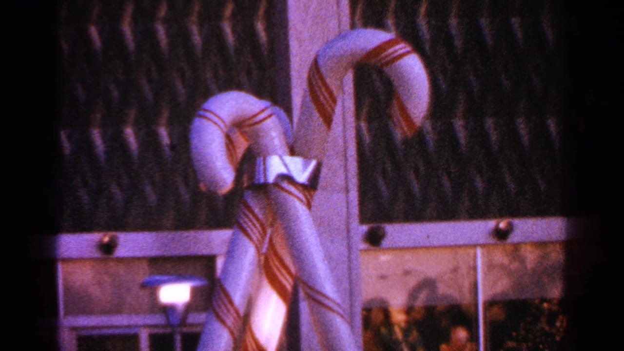 Two large red-and-white striped candy canes tied with a silver bow near dark glass.