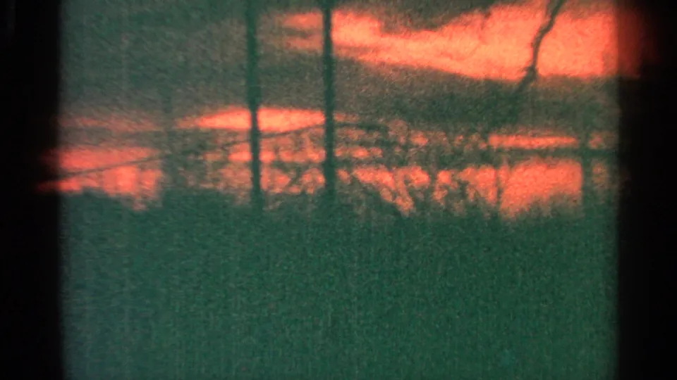 1964 Milwaukee 8mm frame with a soft orange sky, dark window-like divisions, and dense grain as the scene turns abstract.
