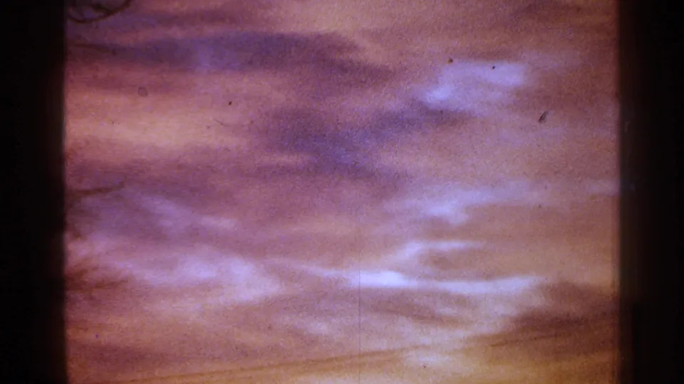 1964 Milwaukee 8mm frame of purple cloud bands and orange lower sky, seen through dark frame-edge shadows.