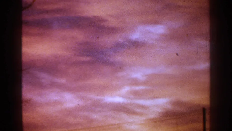 1964 Milwaukee 8mm view of pink-purple clouds with a faint vertical pole silhouette at the right edge.