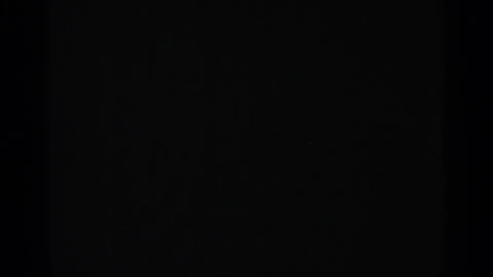 Dark 8mm frame from the Milwaukee sky sequence, showing near-black exposure and faint film texture.
