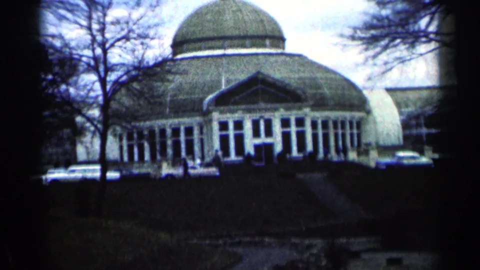 Closer 1964 Minnesota 8mm view of the domed glass-front building, with parked cars and visitors visible near the entrance.