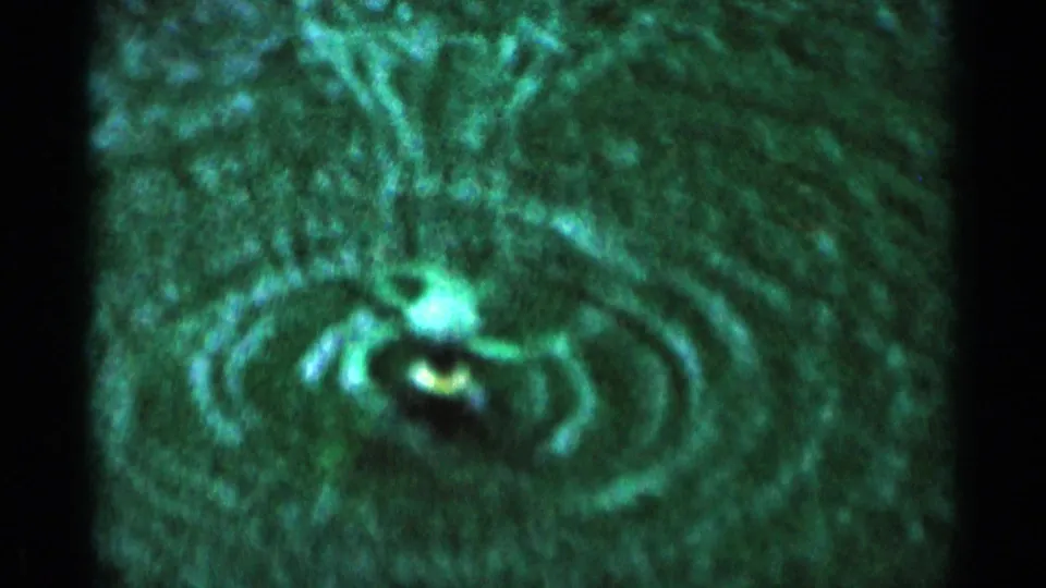 Close 8mm view of a green-tinted spinning lawn sprinkler forming arcs of water on grass in Minnesota, 1964.