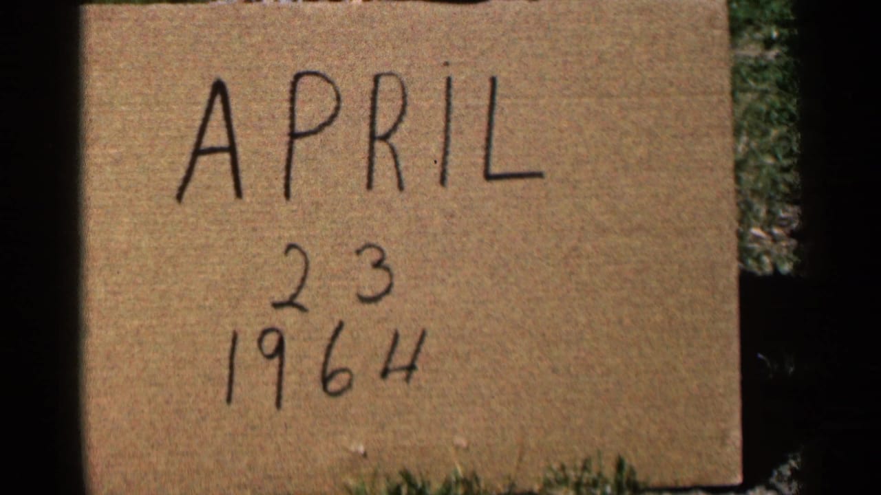 Handwritten cardboard sign reading April 23, 1964 on grass.