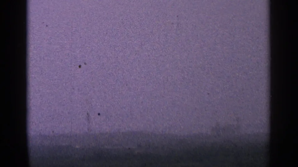 1964 Minnesota 8mm frame with a hazy, low horizon and pale overcast sky, softened by film grain and color shift.