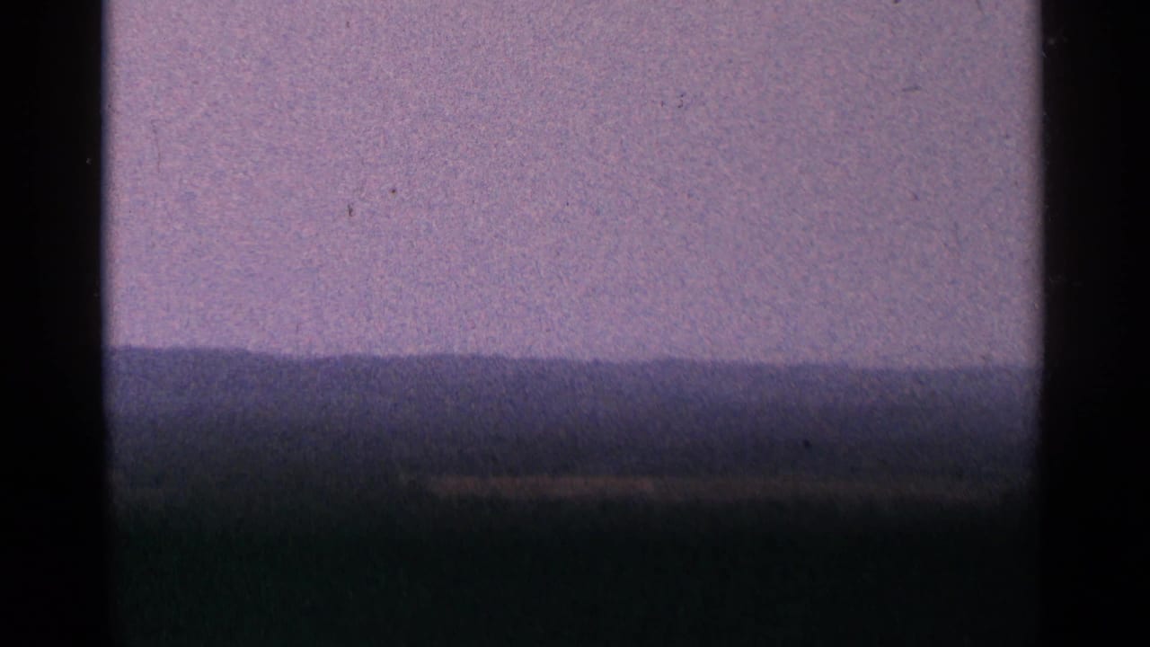 Purple-toned horizon or sky with dark foreground and black film border.