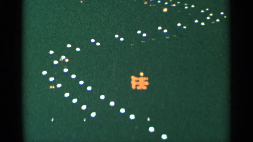 1964 Minnesota 8mm night frame with scattered white lights crossing a green-black field and a small orange illuminated shape.