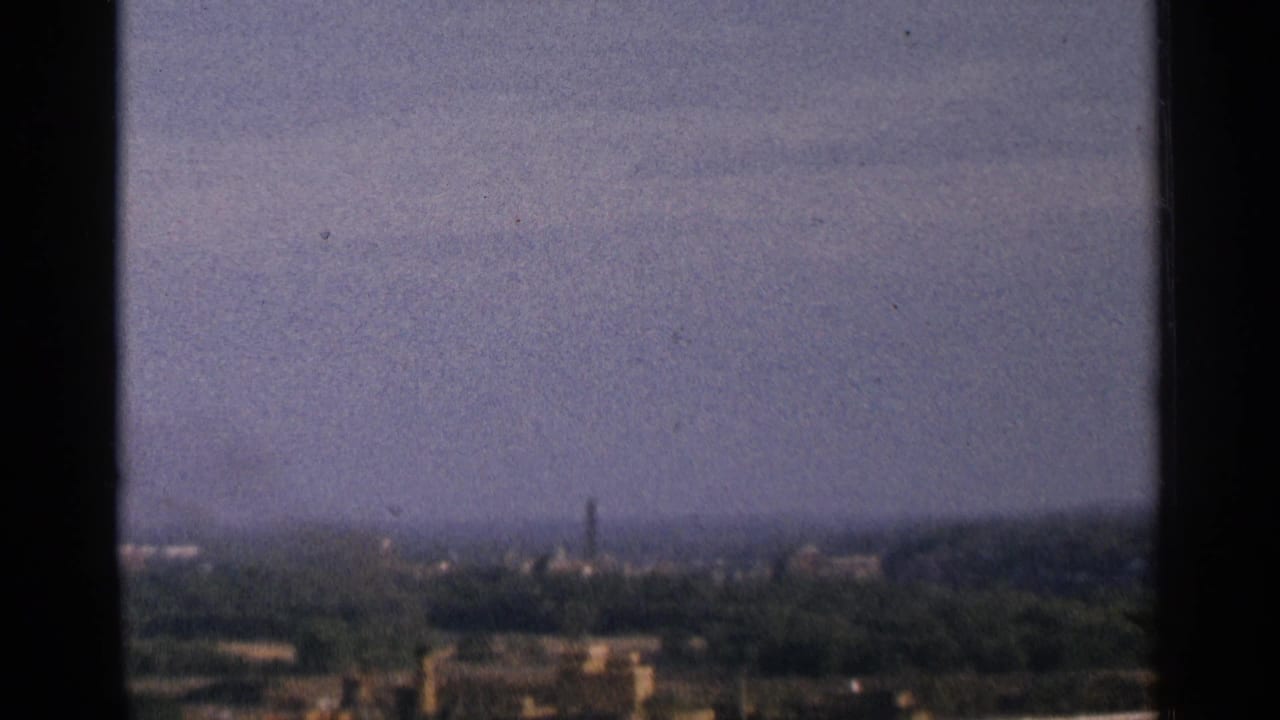 Hazy distant city view framed by dark vertical edges above a river landscape.