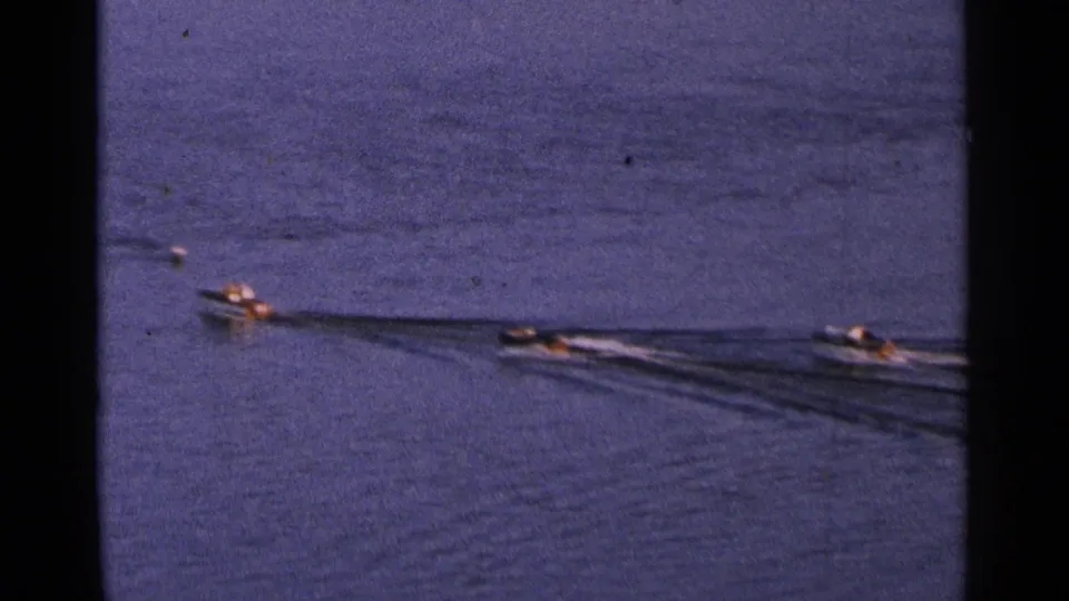 Small motorboats move across a Minnesota lake in 1964, with tiny occupants and long wakes visible on blue water.