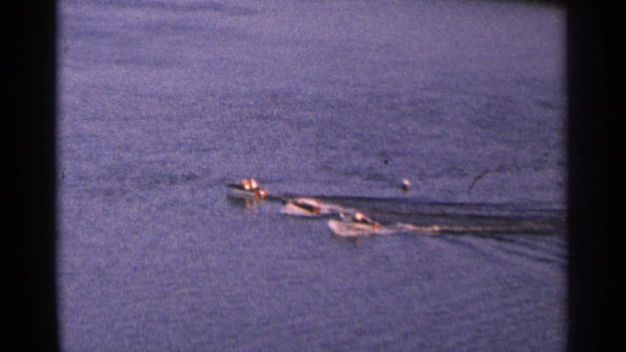 Small motorboats run side by side across open water with wakes spreading behind them.