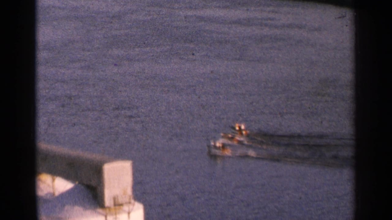 Small boat moving across rippled water, seen through dark 8mm frame borders.