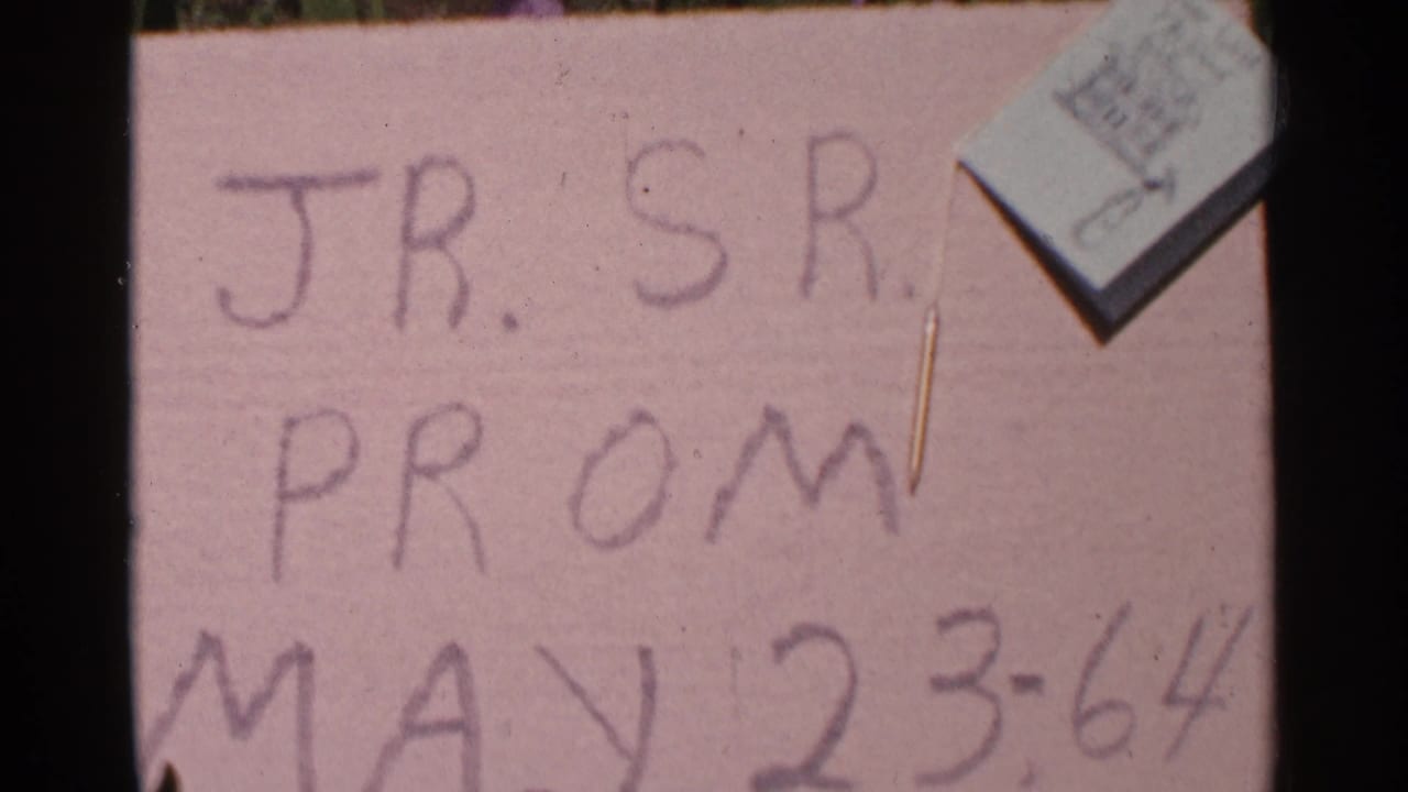 Close view of a pink handwritten sign reading JR. SR. PROM MAY 23-64.
