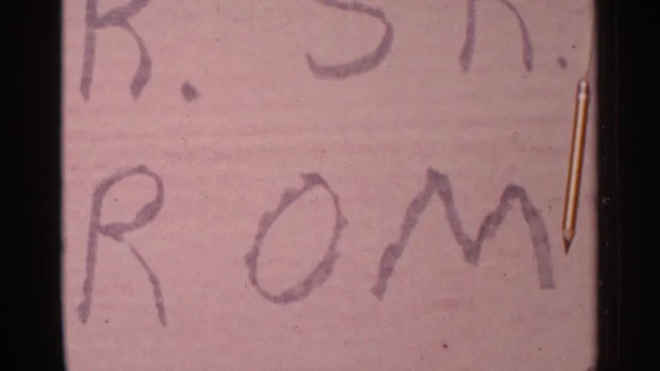 Soft 8mm close-up crops into the handmade prom sign, showing large handwritten letters on pink board.