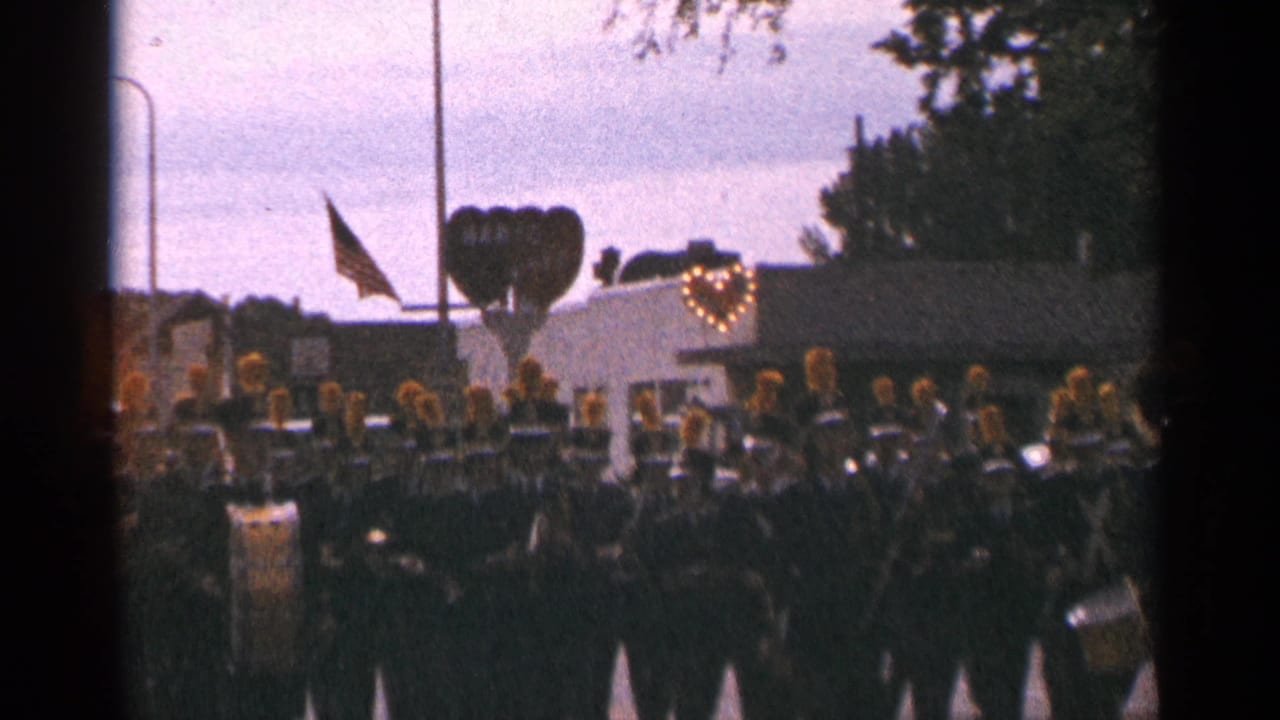 Uniformed marching band moves in formation with a float behind them.