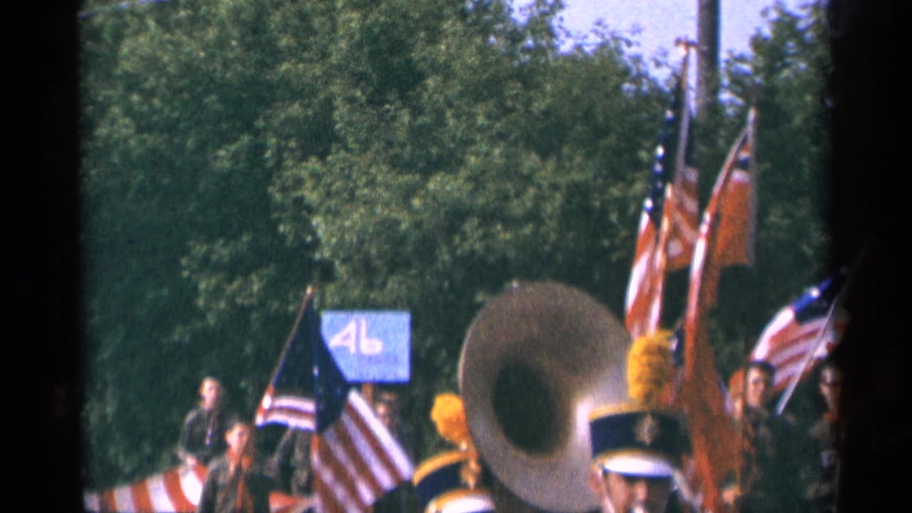 Final contact-sheet frame shows the marching band continuing through Minnesota in 1964, with a sousaphone, American flags, red flag, and yellow plumes visible.