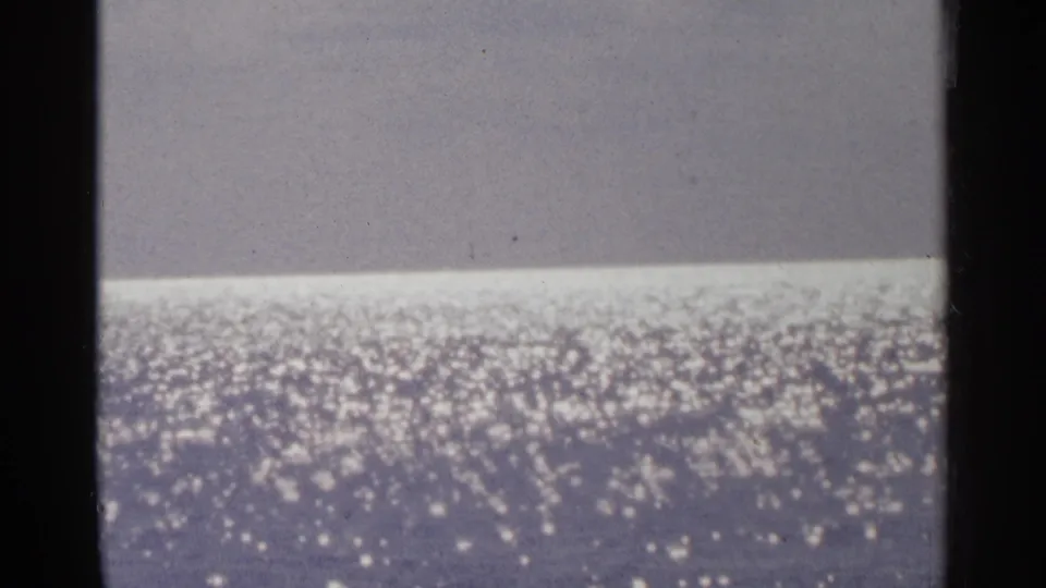 Minnesota 1964 home-movie frame focused on glittering lake water, with a muted horizon and visible film texture.
