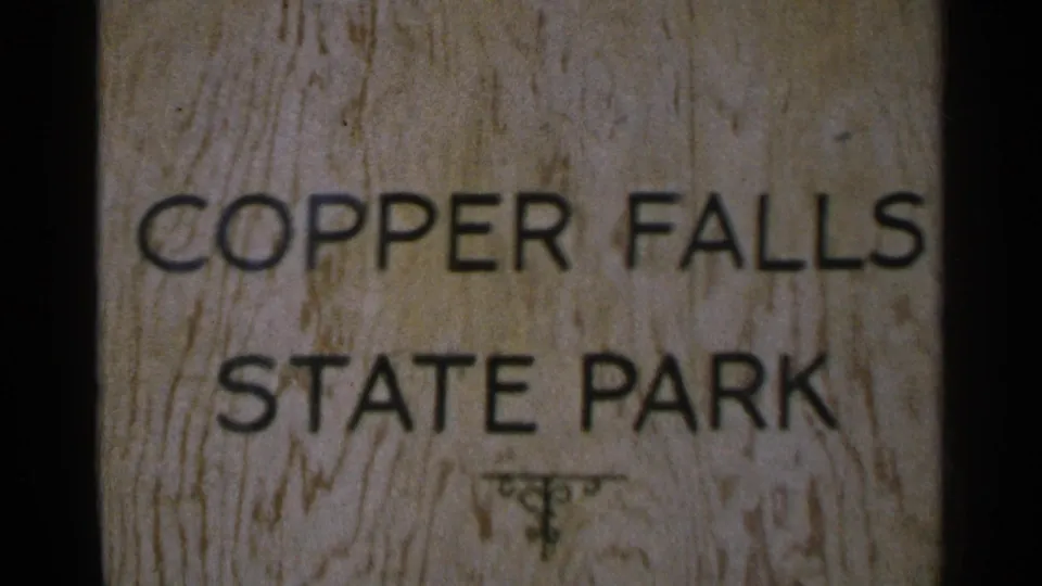 Close 8mm view of a wooden Copper Falls State Park sign with black lettering and visible wood grain.