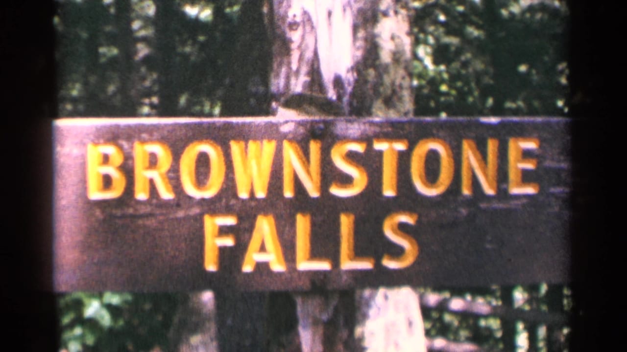 A wooden Brownstone Falls sign appears in front of trees, confirming the Minnesota waterfall location in the 1964 home movie.