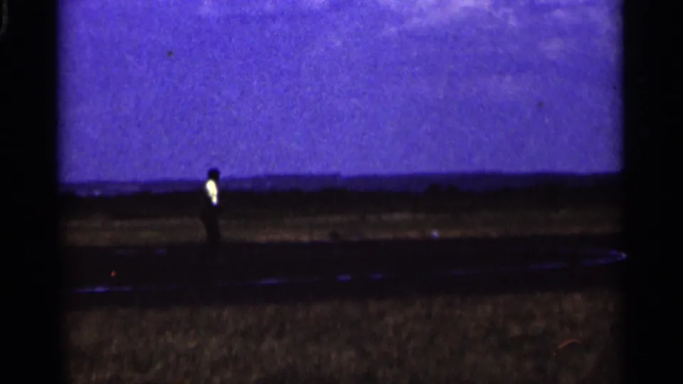 A distant adult figure stands near the grass airfield as the runway and open Minnesota sky fill the frame.