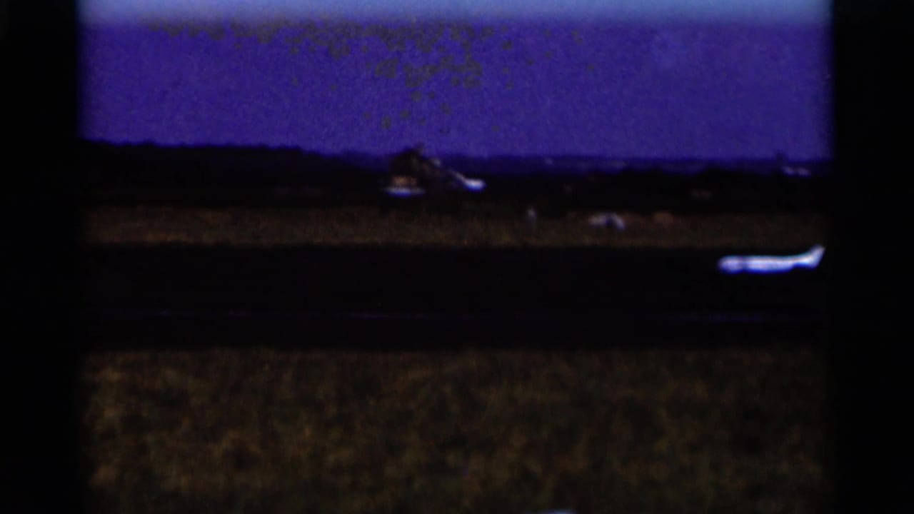 Distant small white airplane near a rural runway under a dark blue sky.