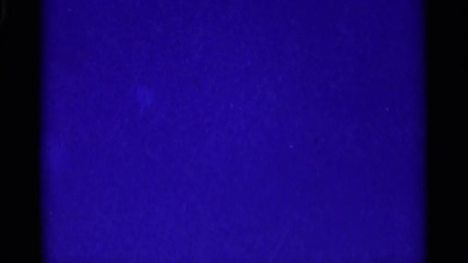 Underexposed 8mm frame dominated by deep blue color, with minimal visible subject detail from the aviation clip.