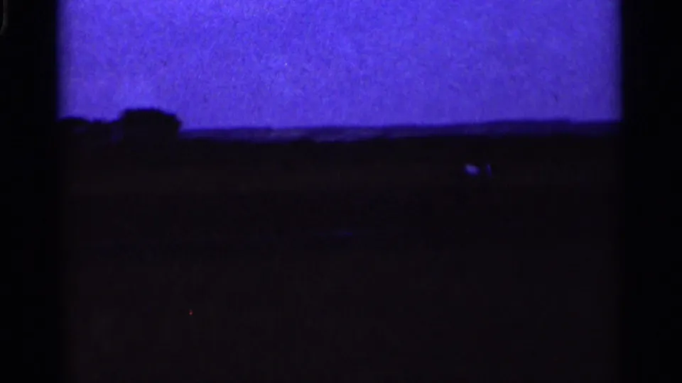 Soft 8mm frame from 1964 Minnesota showing the grassy landing area and a faint model airplane shape near the strip.