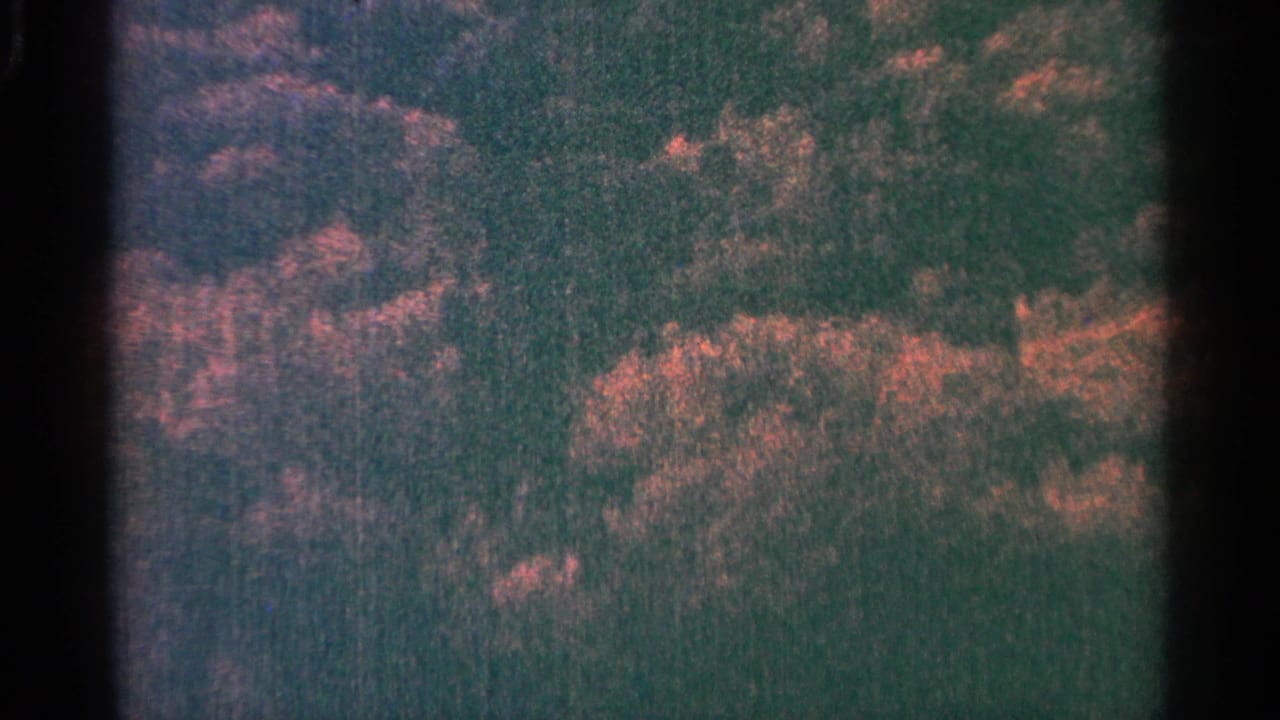 1964 8mm Minnesota footage begins with abstract dark shoreline or cliff-like texture, reddish highlights, grain, and visible film gate edges.