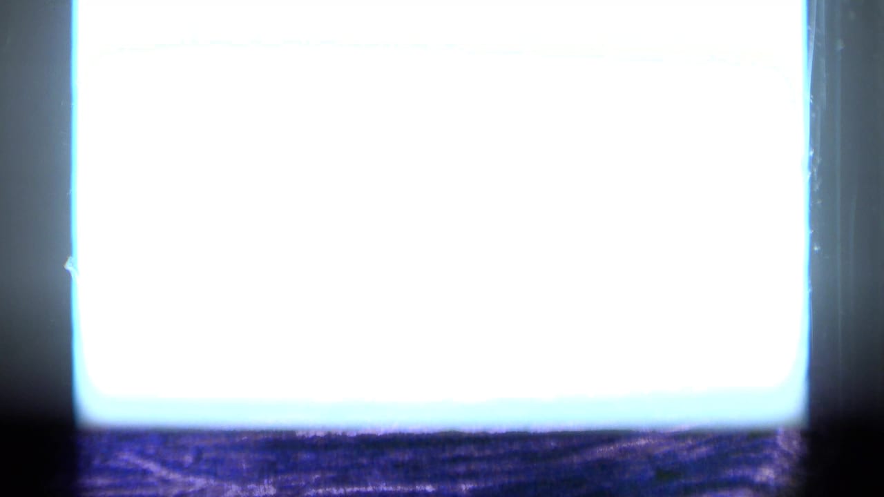 Overexposed bright film area beside dark frame edges and faint tree or ground detail.