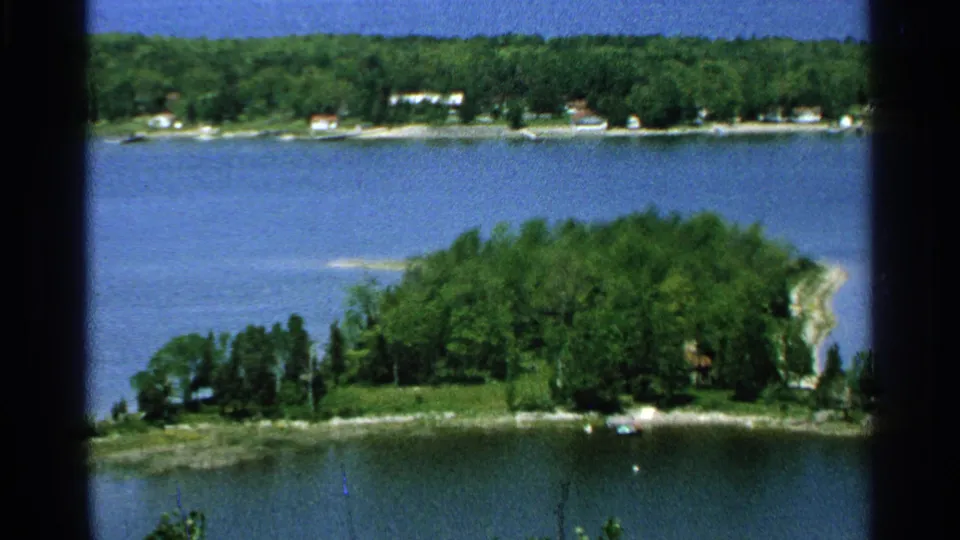 Washington Island, Wisconsin, in 1964, with a wooded lakeshore point, calm blue water, and small houses across the shore.