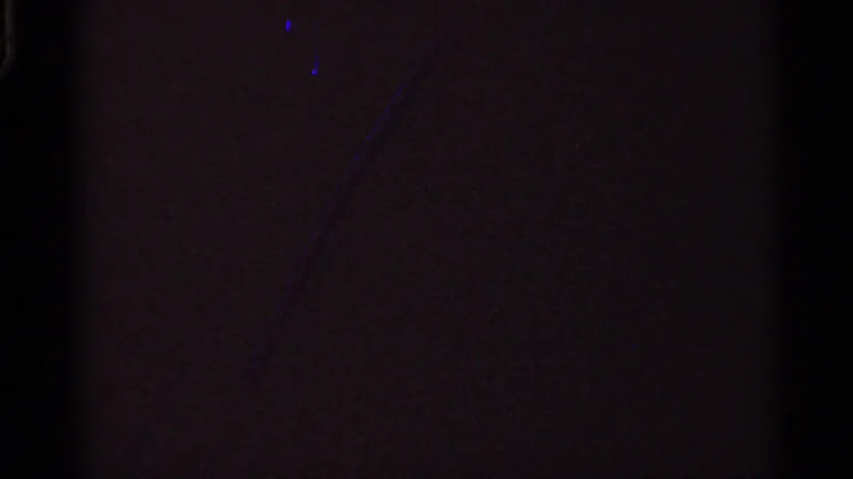 Mostly dark 8mm frame showing grain, faint color shift, and minimal visible scene detail.