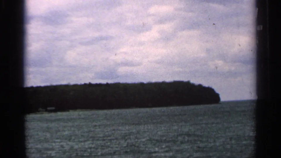 A low, tree-covered Washington Island landmass stretches across the horizon in a handheld 8mm lake view.