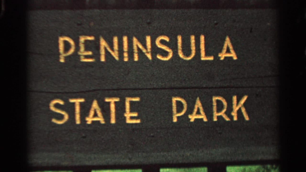 Close view of a dark sign reading Peninsula State Park in gold letters.