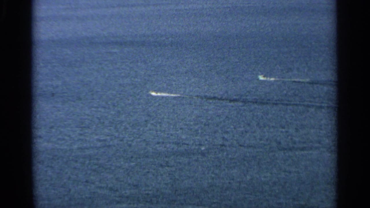 Two small boats move across open water, leaving long wakes.