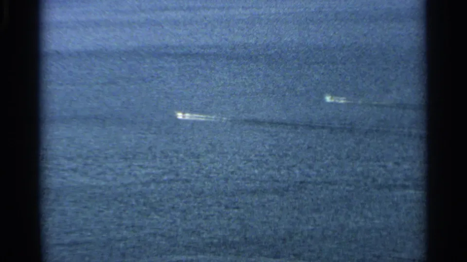Aerial home-movie view of small boats traveling across blue water near Washington Island, with wakes stretching diagonally through the frame.