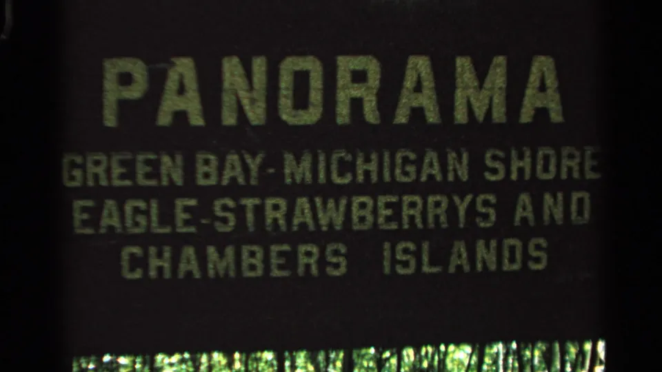 A closer 8mm frame of the travel title card, with green lettering naming Green Bay, Michigan Shore, Eagle, Strawberry and Chambers Islands.