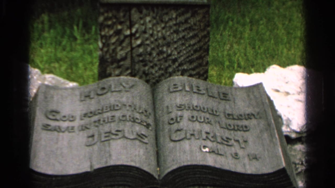 Close 8mm frame of the Bible-shaped headstone in Washington Island, Wisconsin, with carved religious text and grass behind it.
