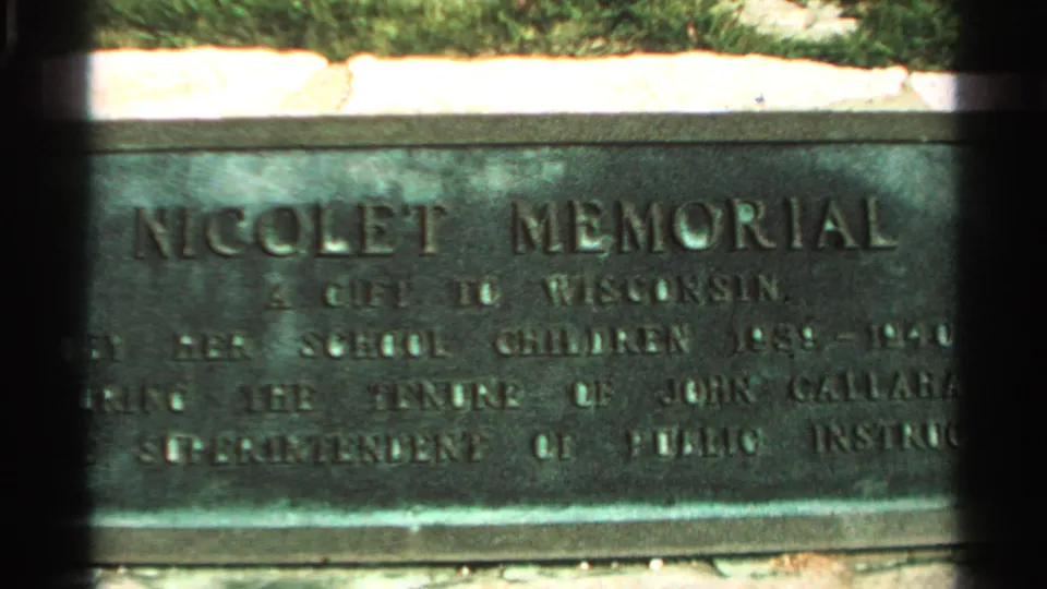 Close-up of the Nicolet Memorial plaque on Washington Island, with engraved lettering, stone or metal surface, and greenery above the marker.