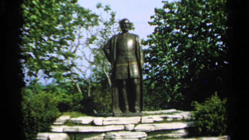 Final view of the Jean Nicolet statue and stone base, surrounded by summer greenery in Washington Island 8mm footage.