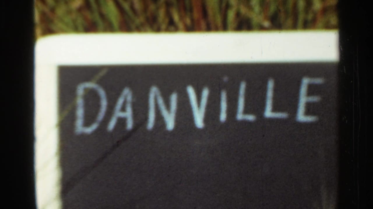 1965 Arkansas frame with the Danville name painted in white on a dark sign, seen close up through soft 8mm focus.