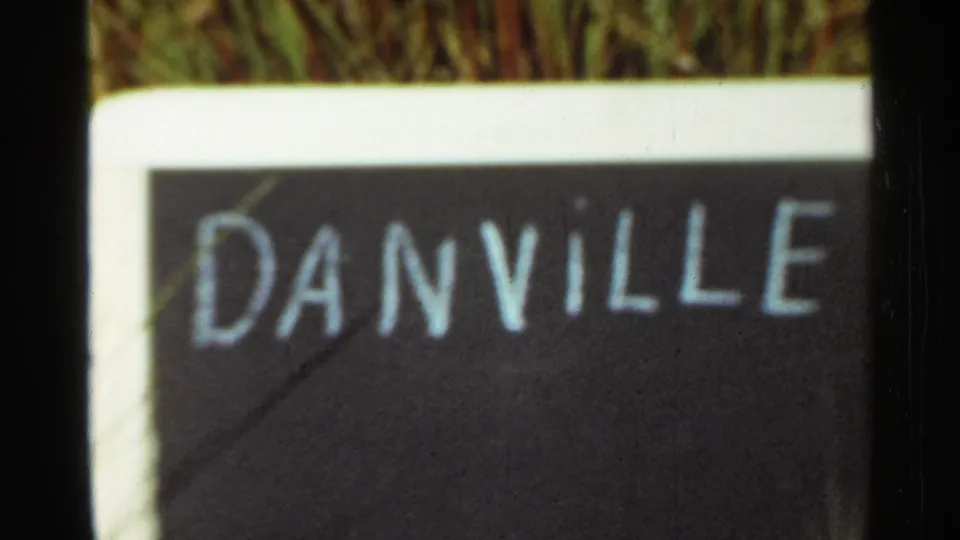 1965 Arkansas frame with the Danville name painted in white on a dark sign, seen close up through soft 8mm focus.