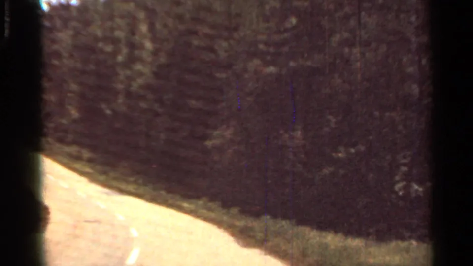 1965 Arkansas 8mm view from a moving vehicle on a curving two-lane road with trees and roadside vegetation.