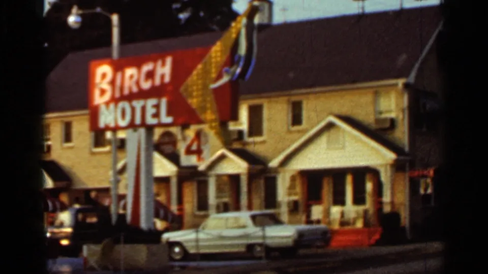 1965 Arkansas 8mm frame of the Birch Motel sign, low-rise lodging facade, and a pale parked car in front.